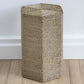 Seagrass side table against light pine floors and white wall.