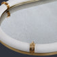 Close up of mirrored tray with brass accents and white rim.