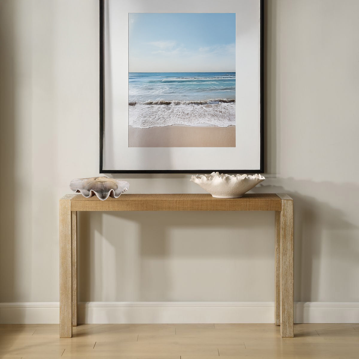 Shell bowl on coastal console table with a photo of the beach in a mudroom.