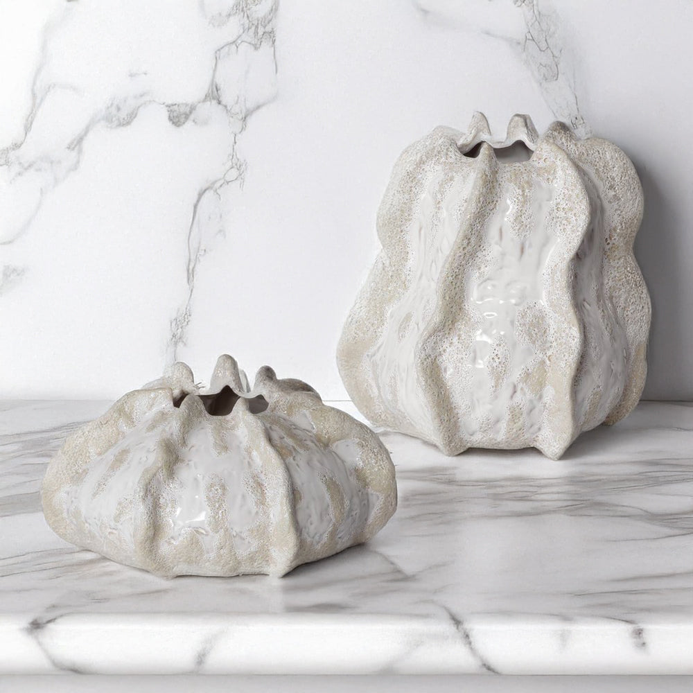 Small ceramic coastal vases on marble counter.