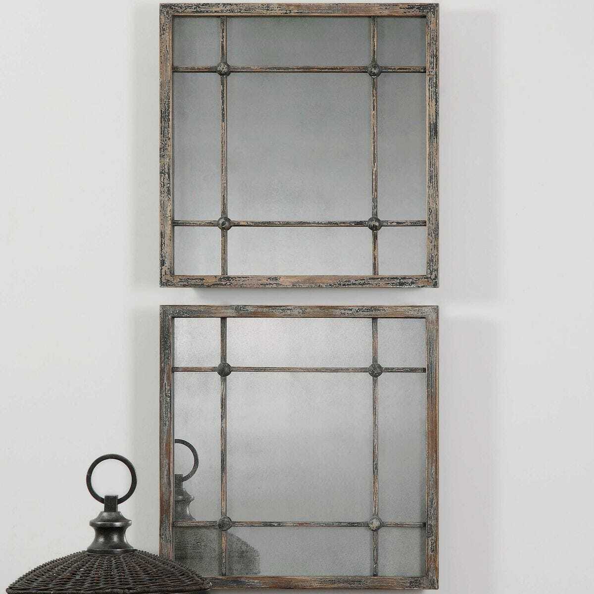 Two rectangular mirrors with decorative frames on a white wall.