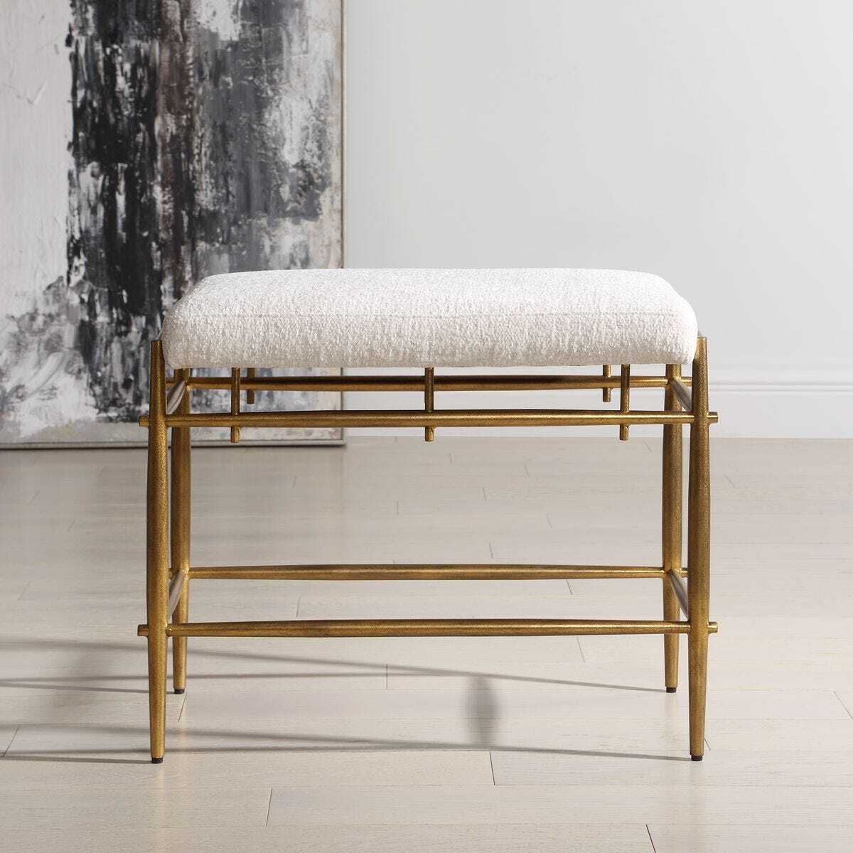 Gold frame bench with white cushion in a minimalistic room.