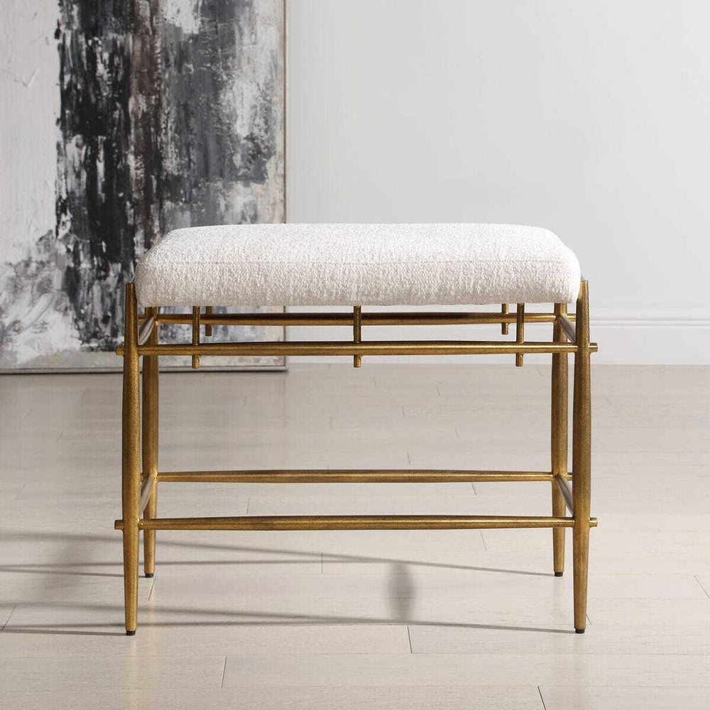Gold frame bench with white cushion in a minimalistic room.