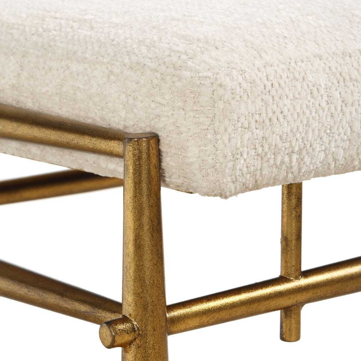Close-up of a stool with gold metal legs and white textured cushioned seat.