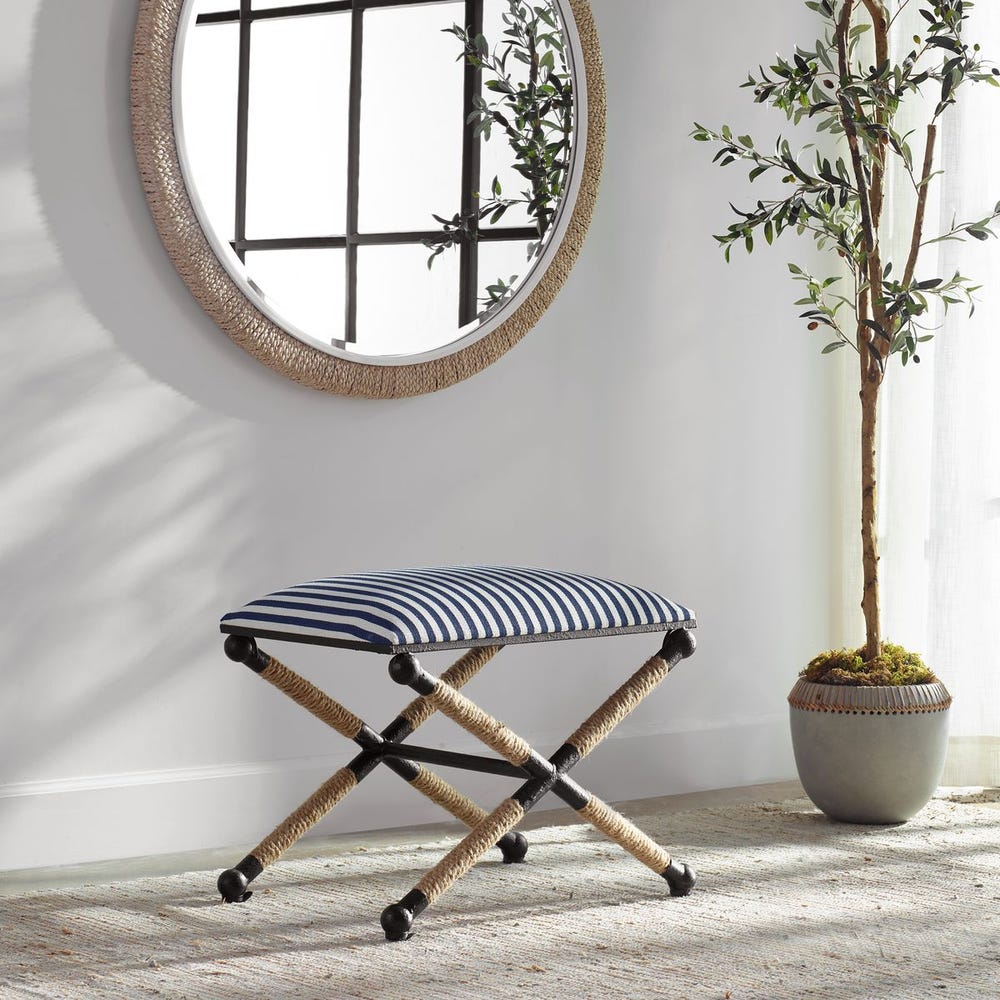 Striped stool in a room with a round mirror and a plant.
