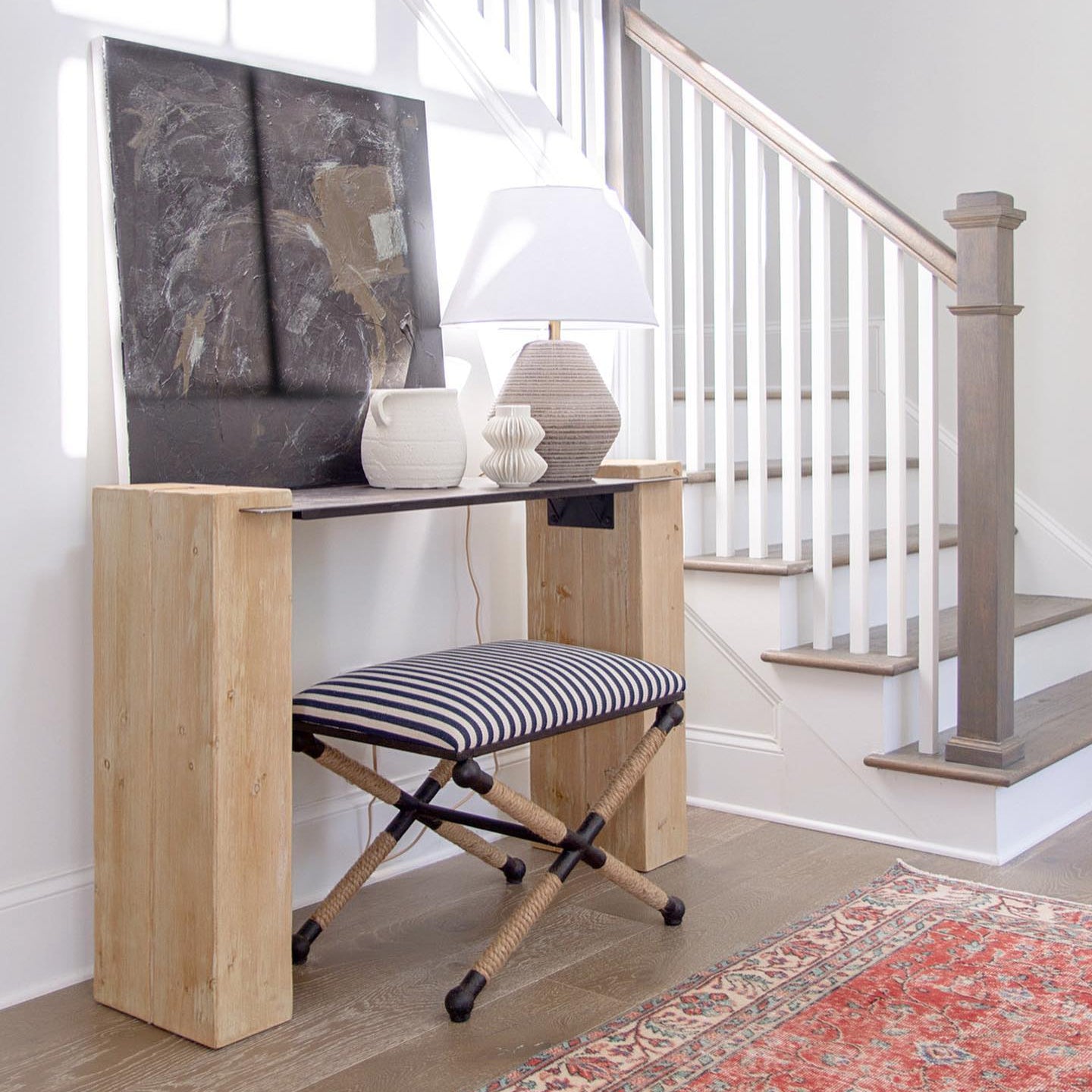Small wooden desk with a striped stool in a home setting.