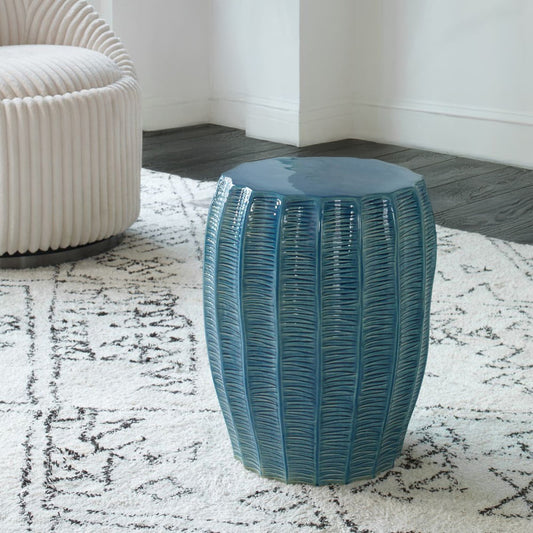 Teal garden stool in living room on chic white carpet with decorative chair