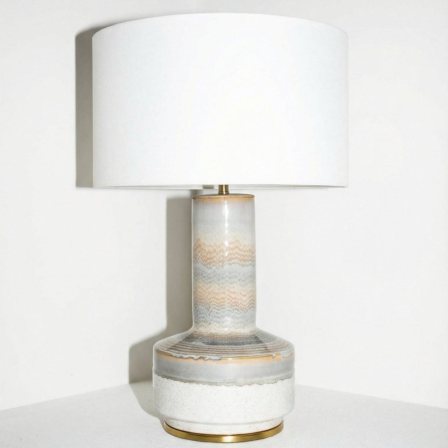 Table lamp with a marble-like base and white shade on a white surface.