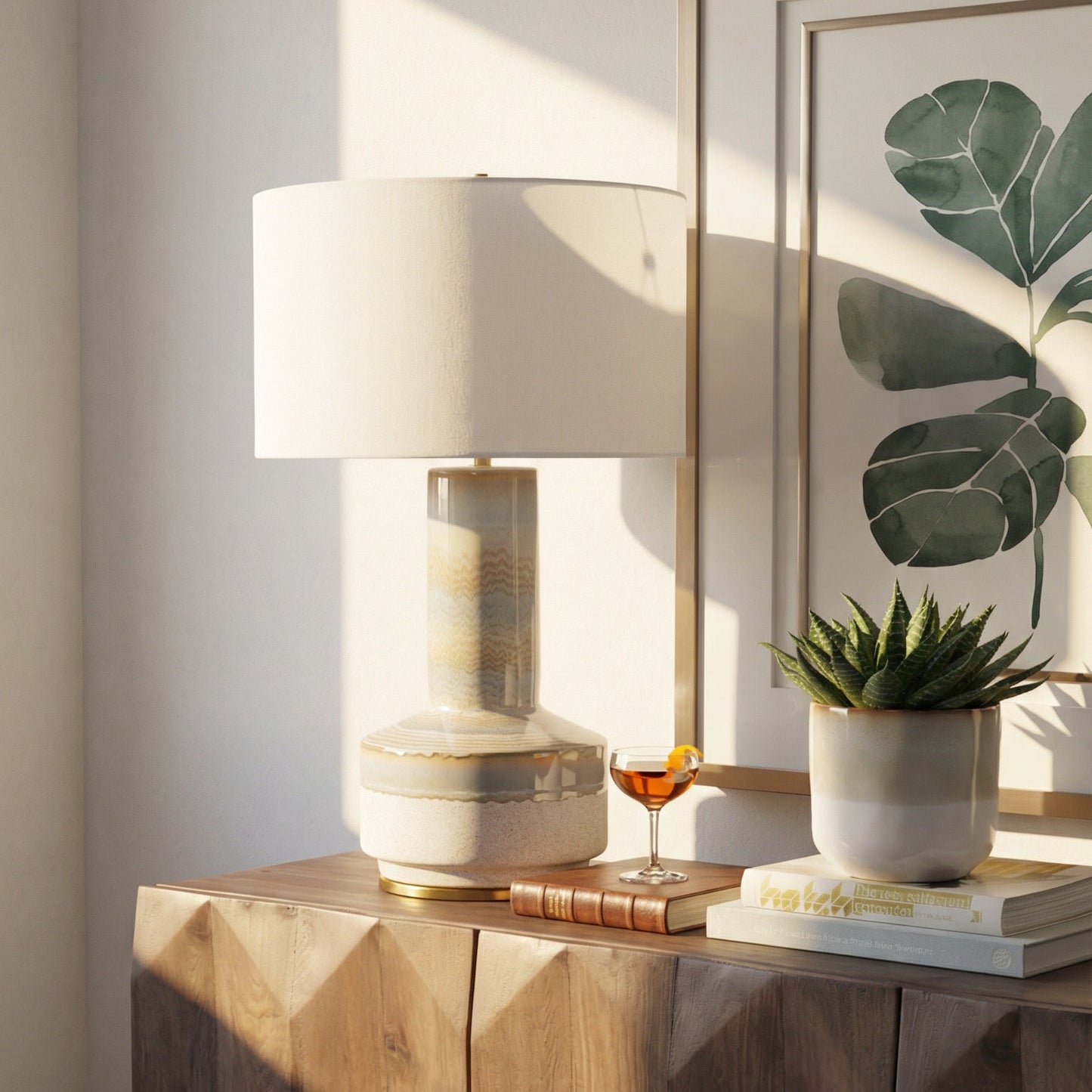 Wooden side table with a lamp, plant, and framed artwork in a room.