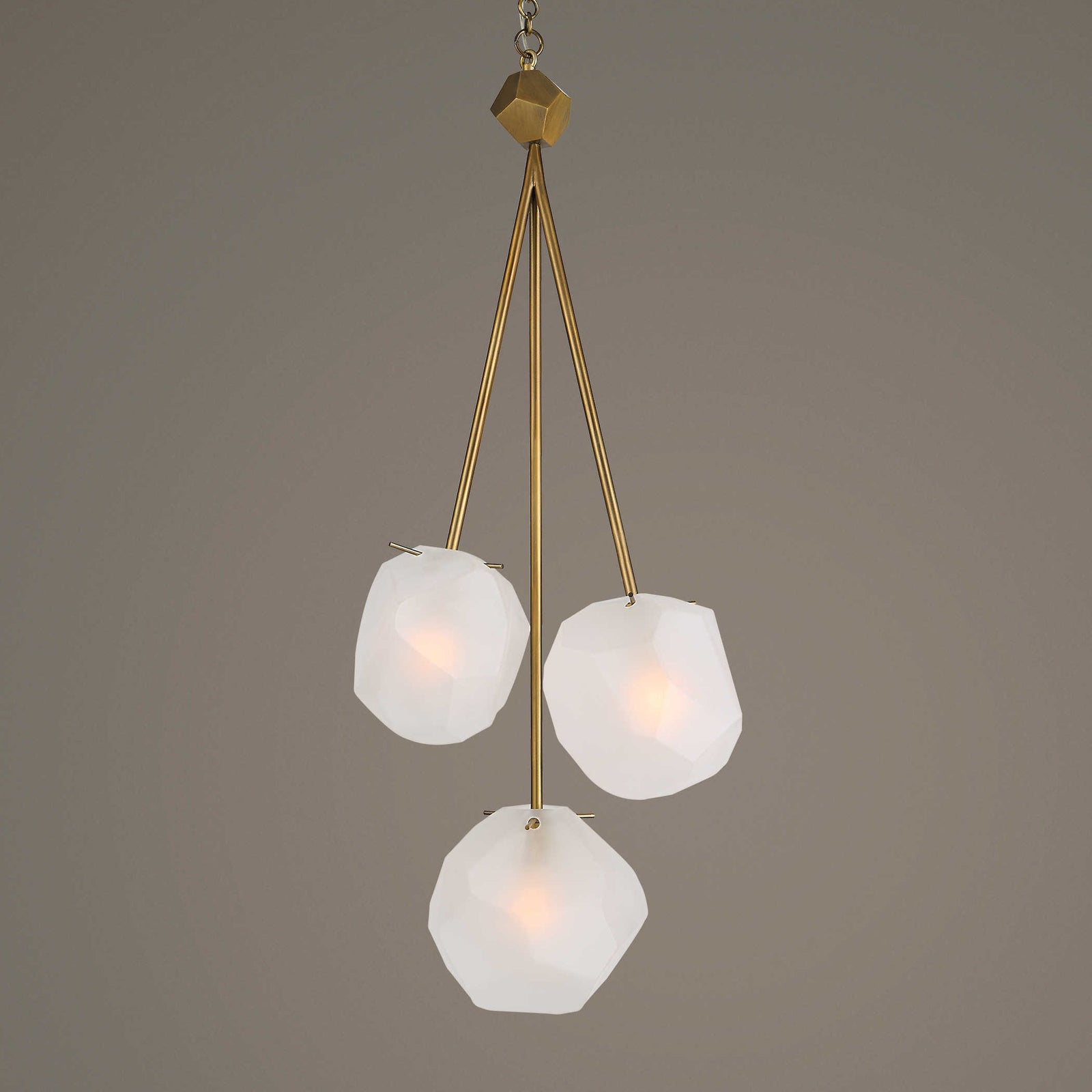 A three-light pendant light fixture with frosted glass shades and a matte antique brass finish.