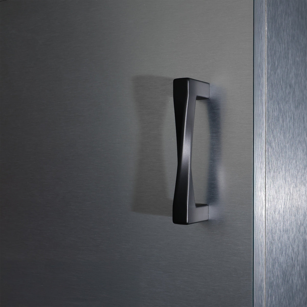 Matte black cabinet handle on a textured stainless steel cabinet door.