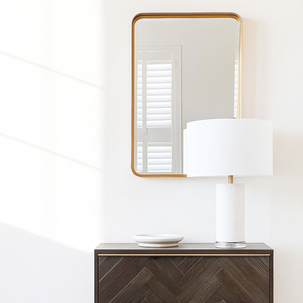 Wooden dresser with chevron pattern and gold frame, mirror above, white lamp on surface.
