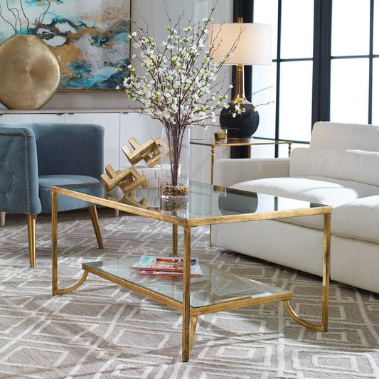 Two-tiered coffee table with glass top and gold metal frame on a white background