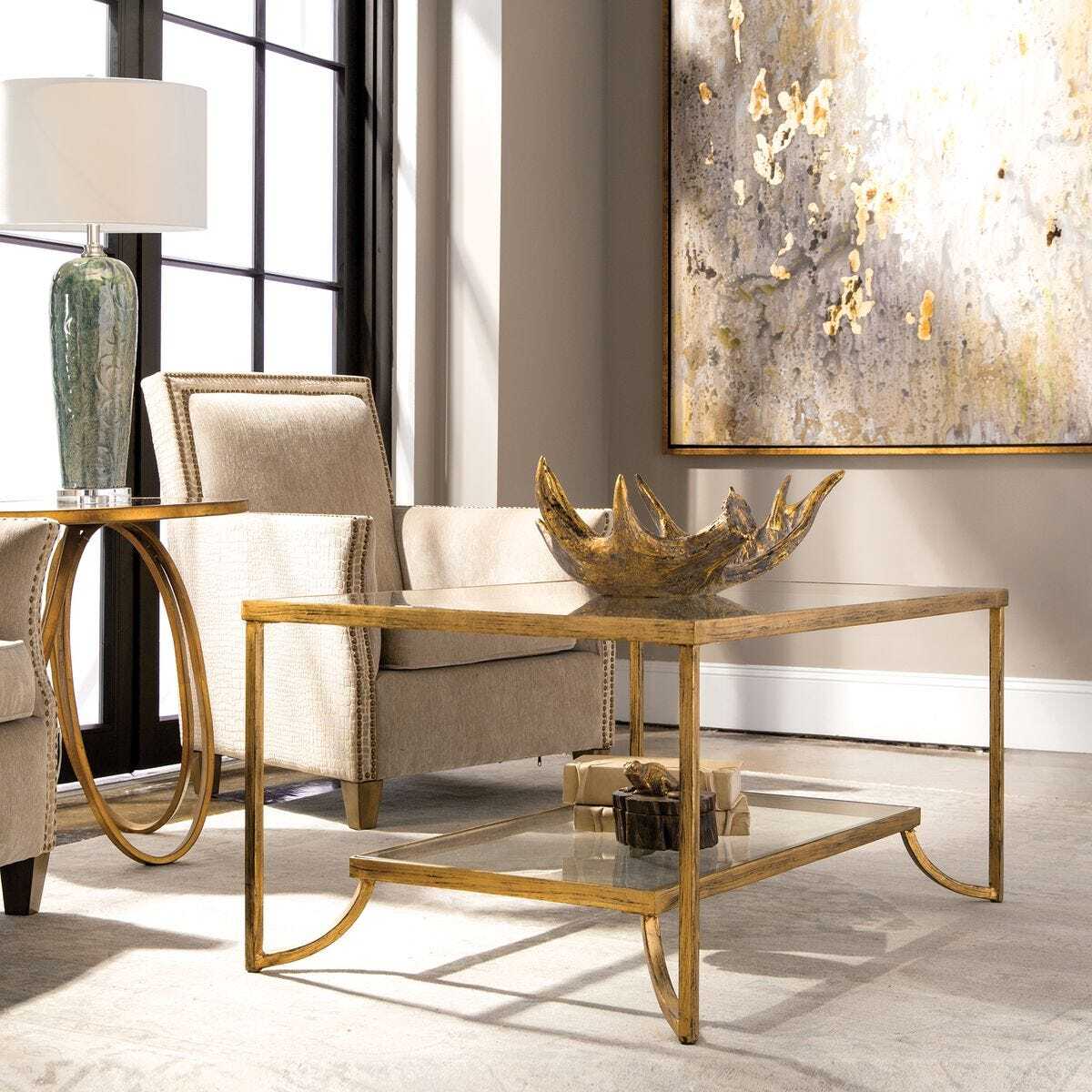 Living room with gold coffee table, armchair, and abstract painting.