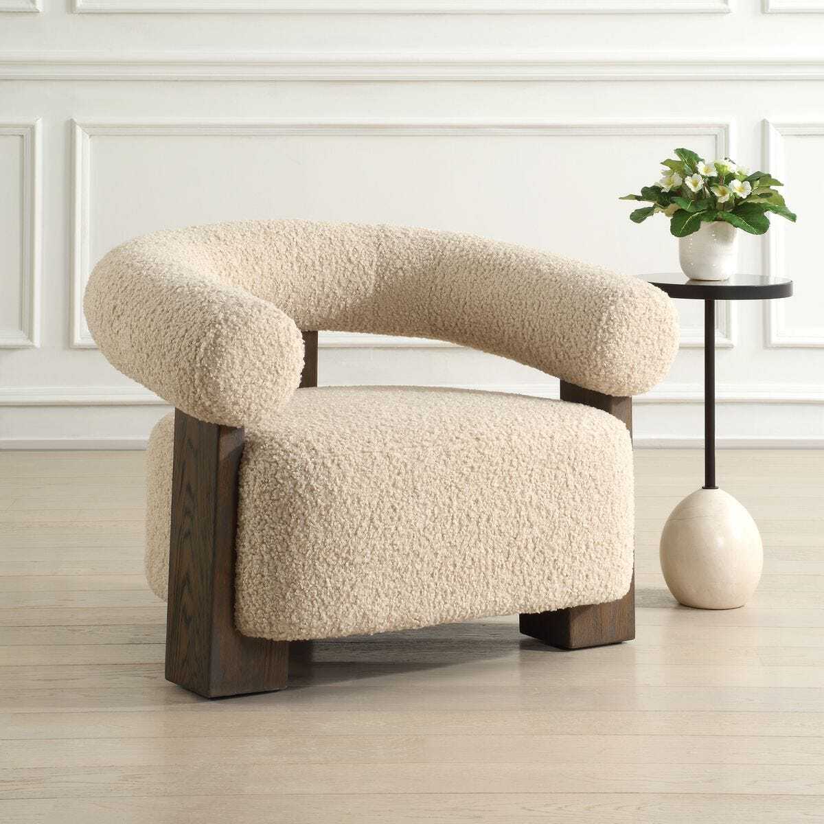 Modern beige armchair with wooden legs in a minimalistic room.