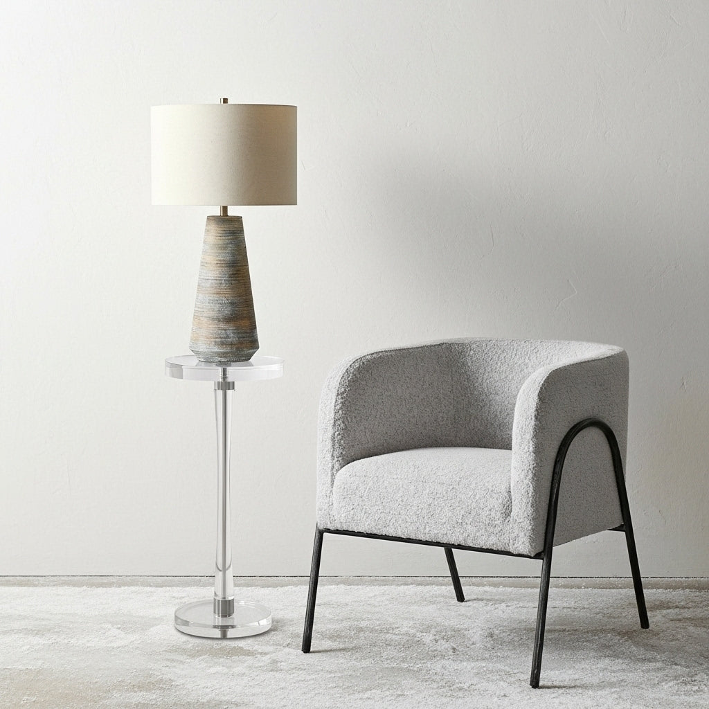 Gray armchair with a lamp on a small table against a white wall.