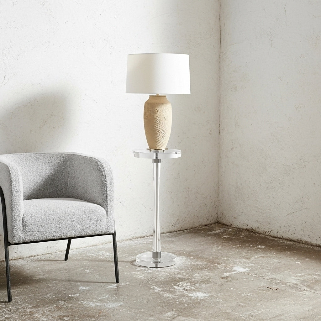 Modern lamp on a small table next to a gray armchair in a minimalistic room.