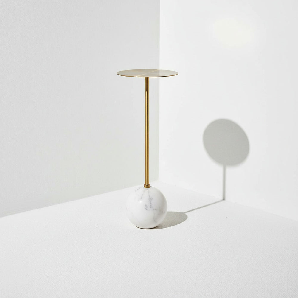 White marble and brass side table in corner of white room.