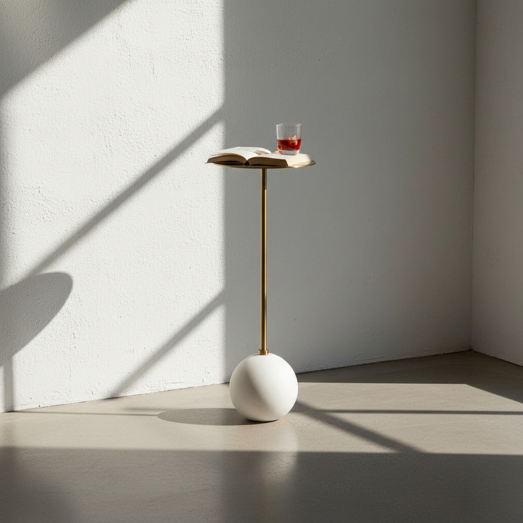 White and brass side table with vermouth and book on top.