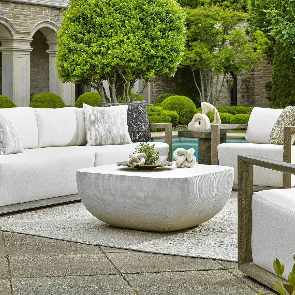 Outdoor patio setting with white furniture and a stone coffee table.