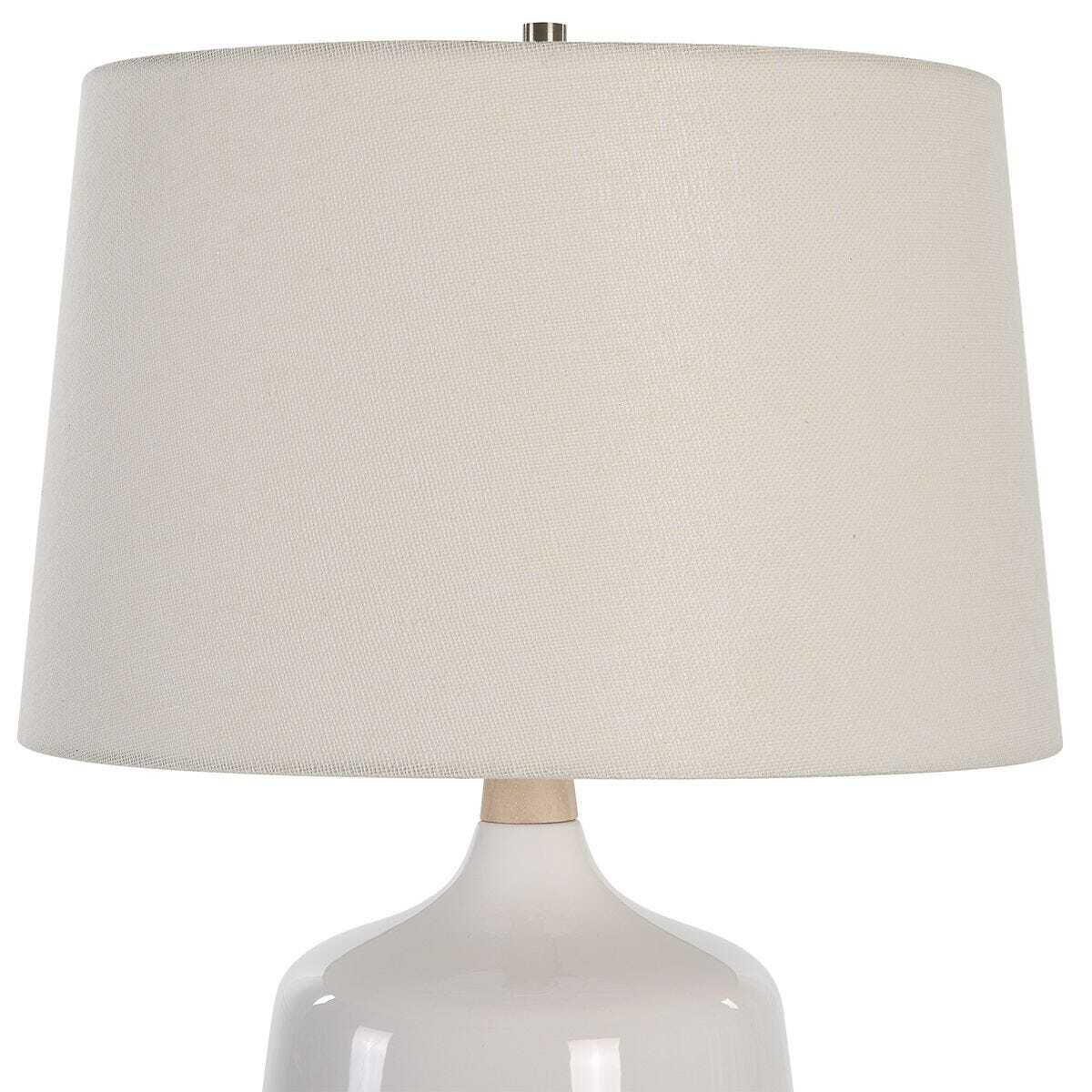 White ceramic table lamp with a beige fabric shade on a white background