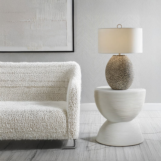 White boucle sofa and white hourglass side table with modern lap and abstract art.