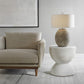 Beige sofa and white hourglass side table with modern lap and abstract art.