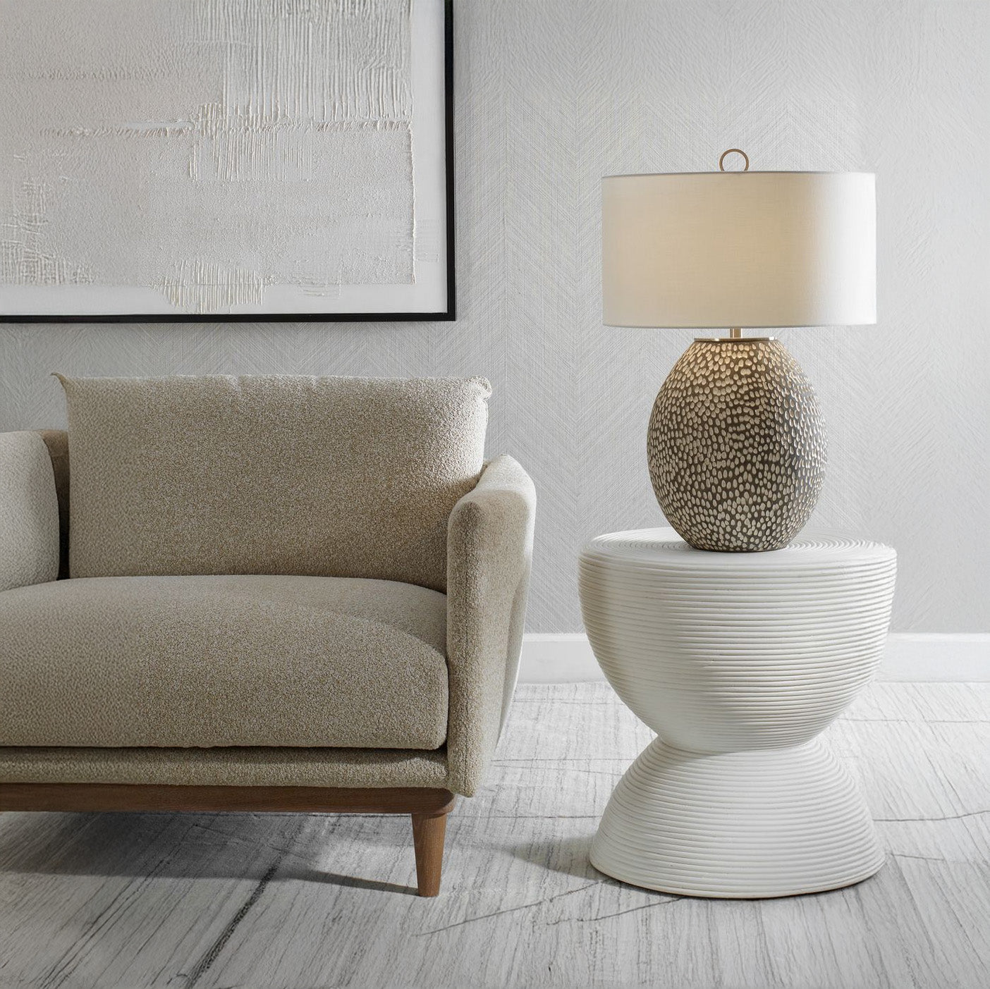 Beige sofa and white hourglass side table with modern lap and abstract art.