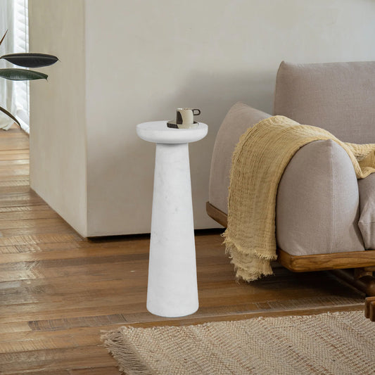 White marble drink table with coffee cup on it's surface next to a sofa with a taupe rug.