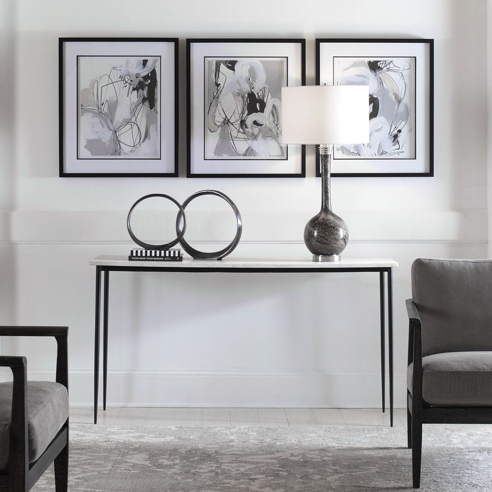 Modern interior with a console table, lamp, and abstract art on a white wall.