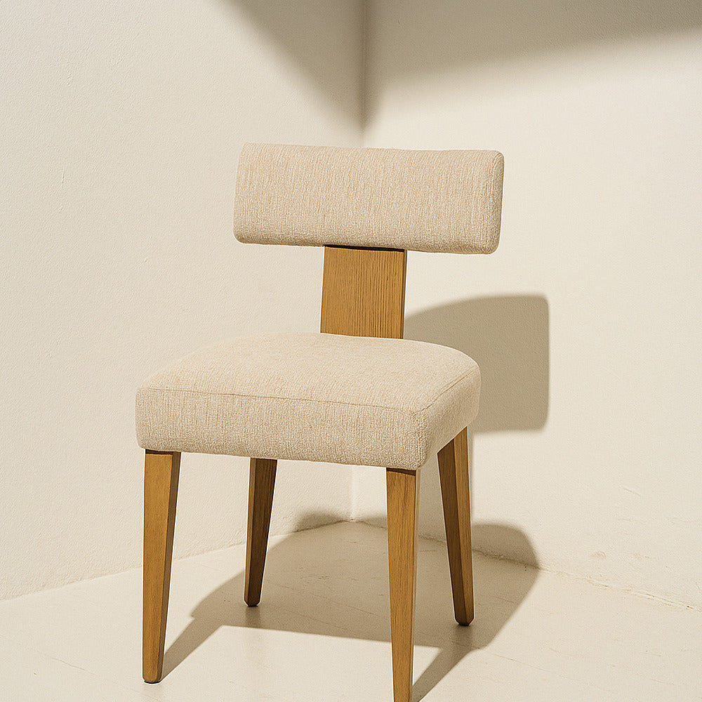 Beige upholstered chair with wooden legs on a neutral background