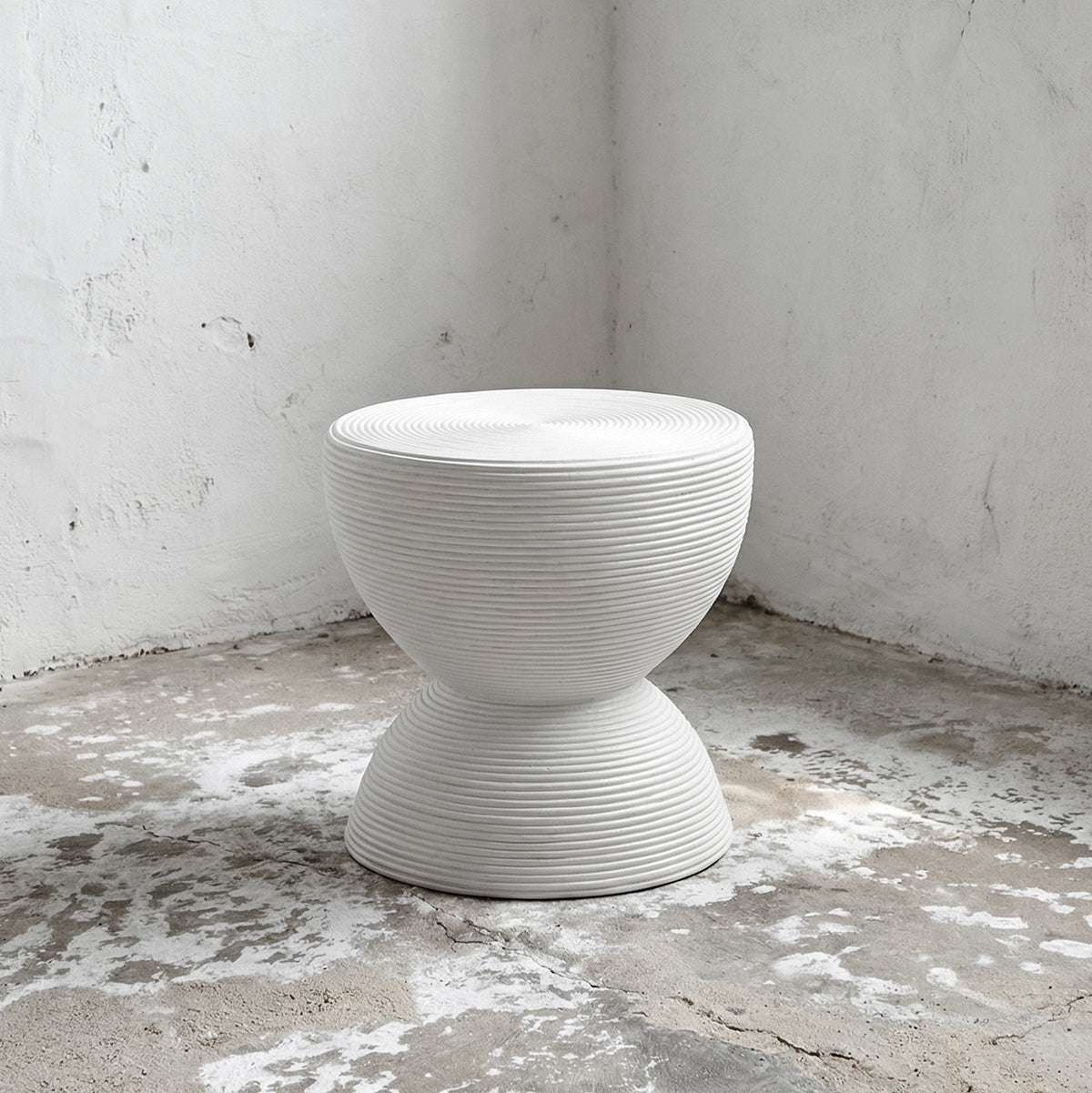 White textured stool on a concrete floor with a white wall background