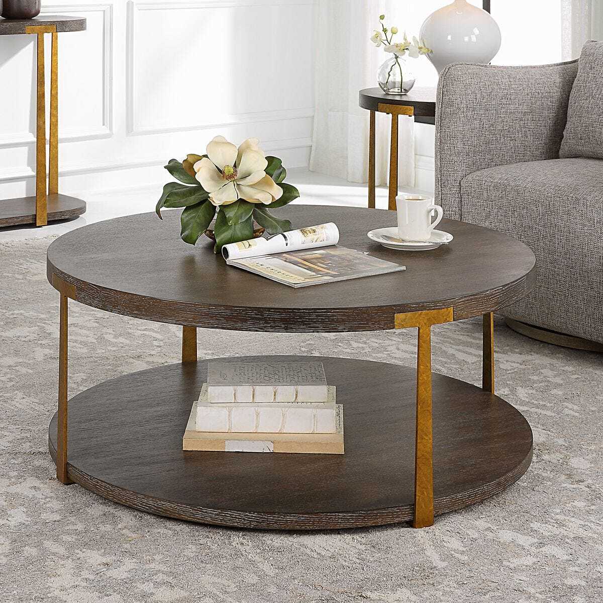 Round wooden coffee table with gold legs in a living room setting.