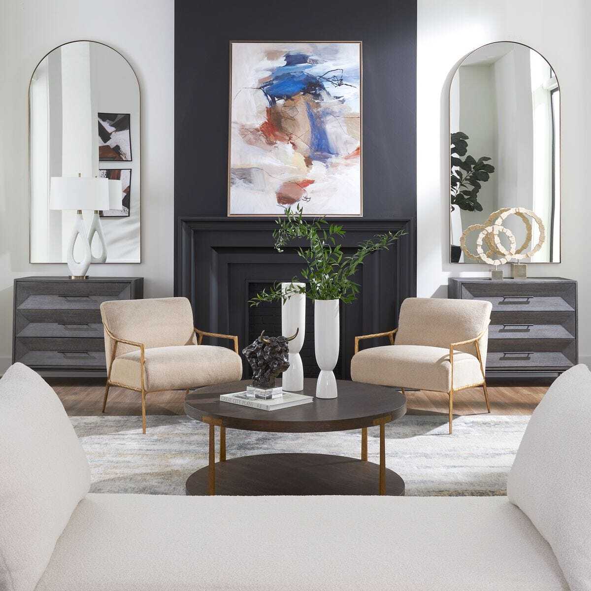 Modern living room with beige chairs, a round coffee table, and abstract art on the wall.