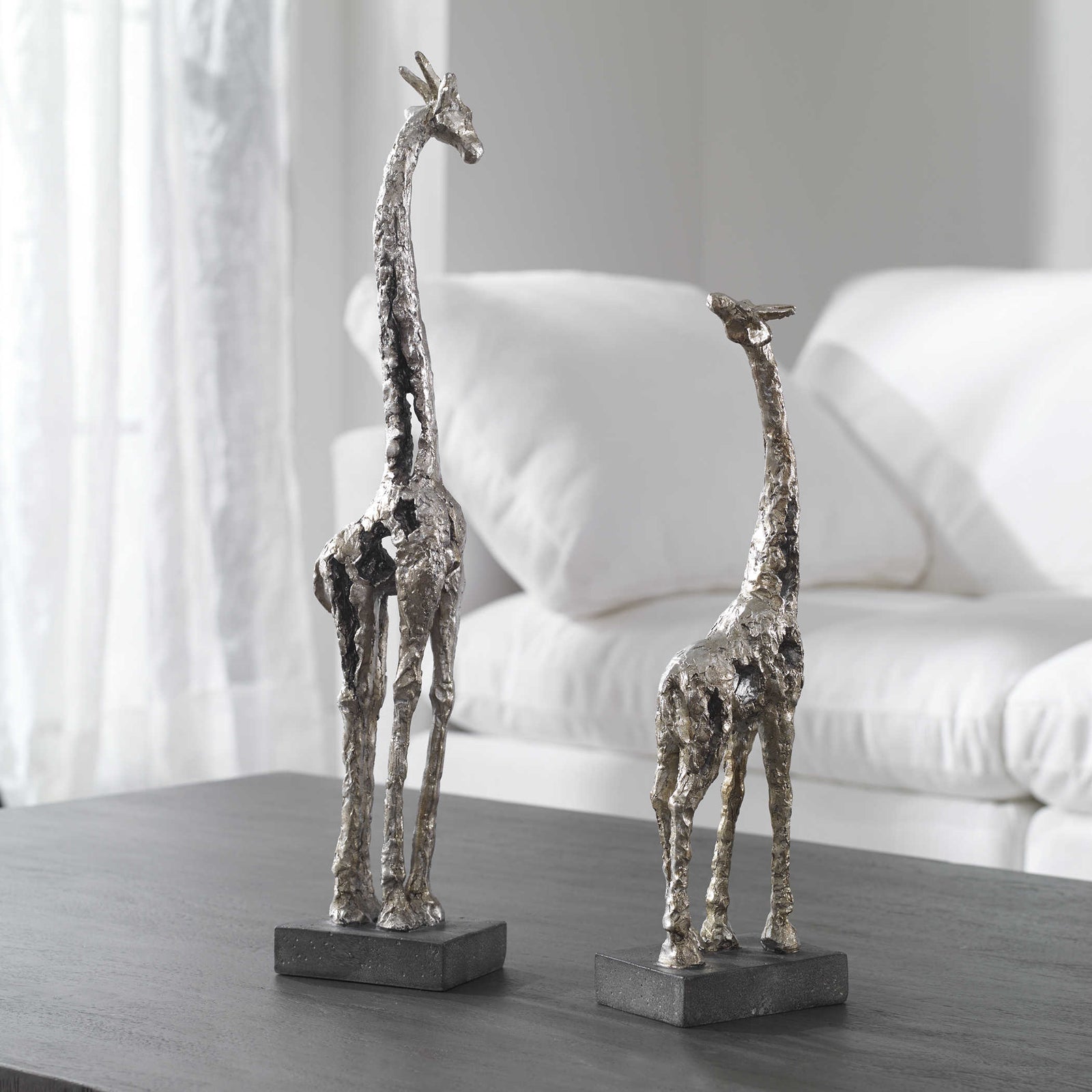 he set of two giraffe figurines feature a molded clay texture with an antique plated metallic silver finish and set atop lightly antiqued concrete bases (set of 2).