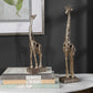 Giraffes setting on a set of books and on a table.