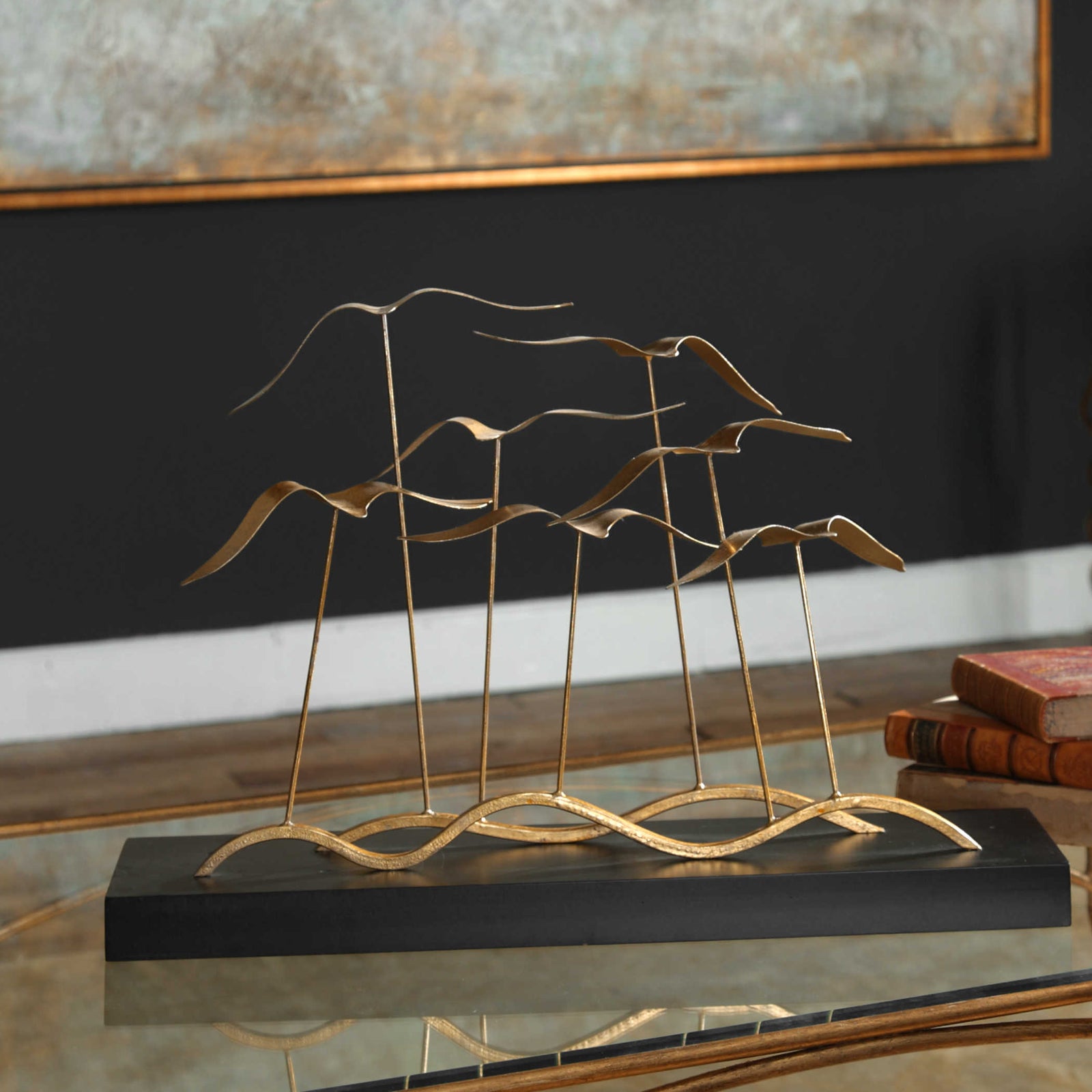 Flock of seagulls, finished in a metallic gold leaf, flying above an aged black distressed wood base.