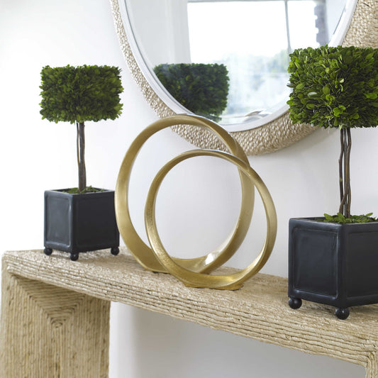 Set of 2 gold aluminum rings standing together on top of a counsel with planters on either side.