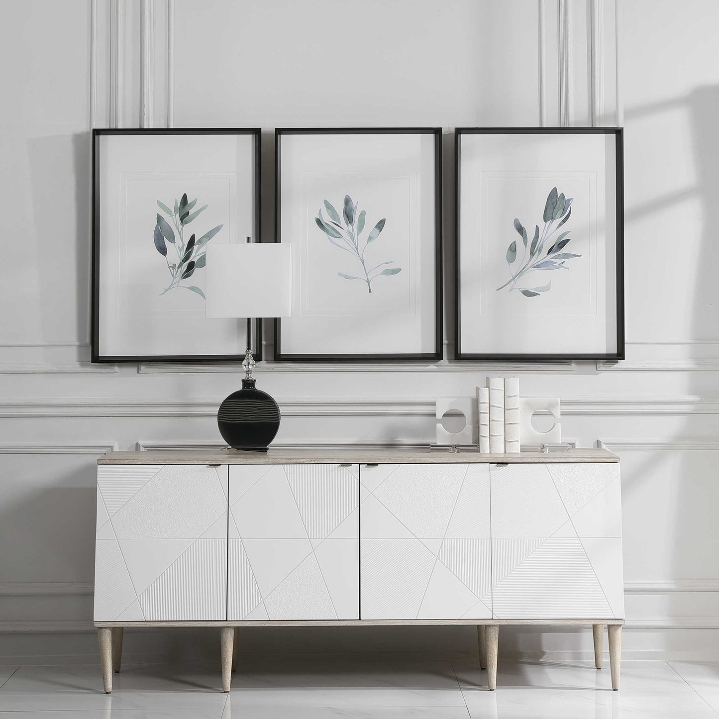 Set of three sage plan prints above a white console in a luxurious living room. 