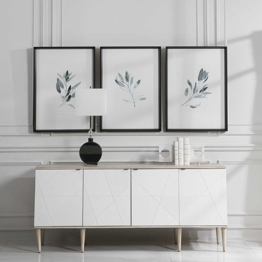 Set of three sage plan prints above a white console in a luxurious living room.