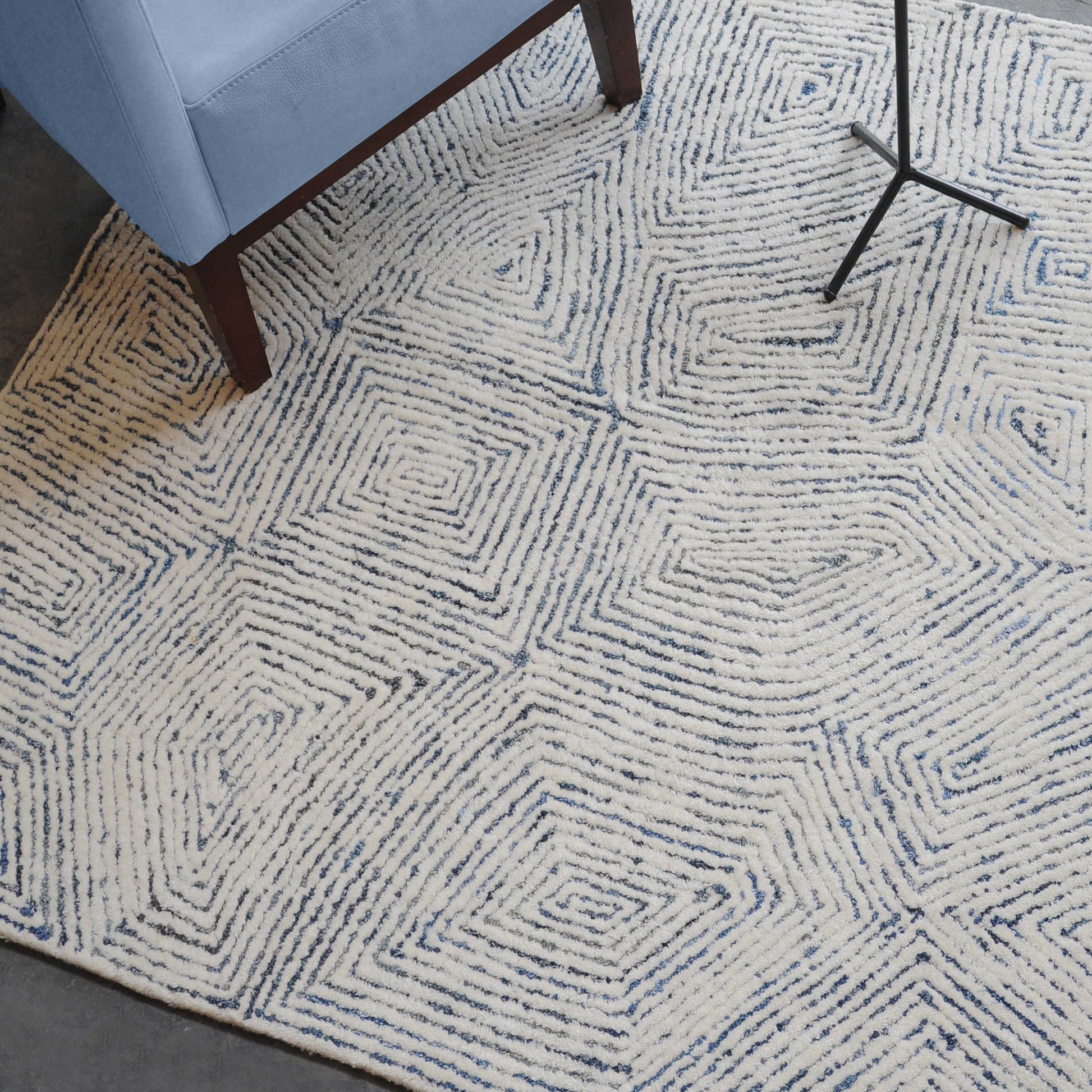 Blue and white alternating lines on a rug with a blue chair and legs of an accent table.