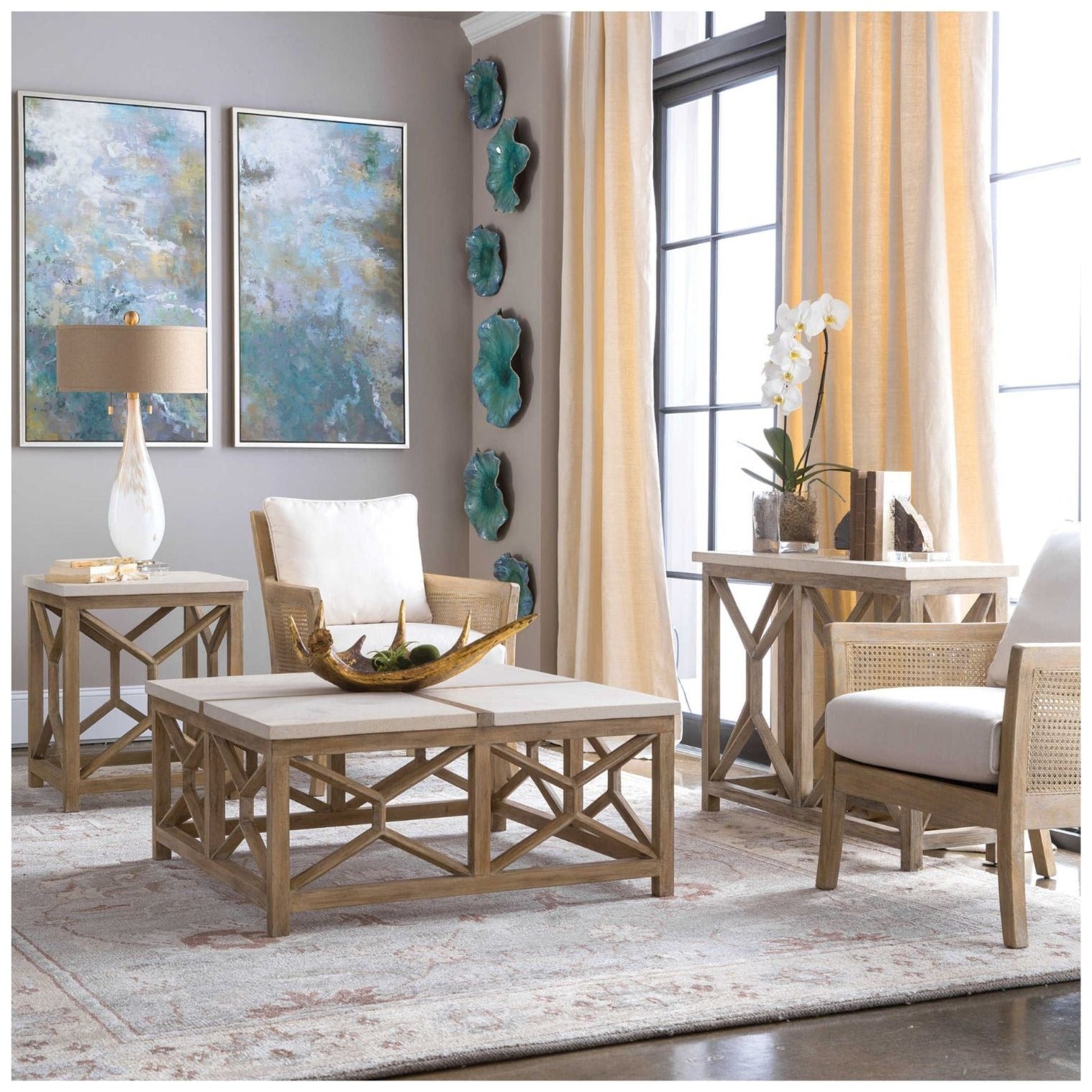 This is a room setting with featured coffee table . Background  has same style end table and console with two woven cane side chairs. Art, a lamp, wall sculptures and an orchid are in room decor.