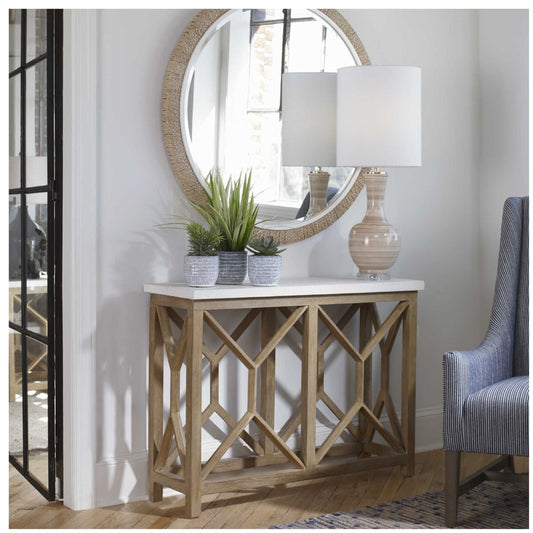 Room setting with console of a natural ivory limestone top, on a geometric base finished in a warm oatmeal wash solid mixed woods shown with round mirror over top..