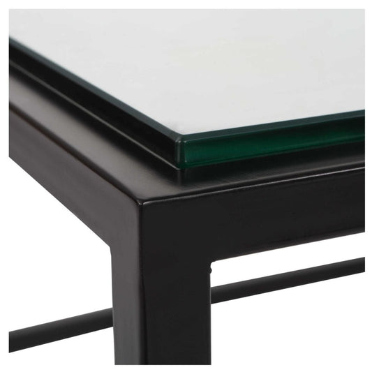Clost uo of this modern coffee table sports a streamline iron frame finished in satin black paired with an inset tempered glass top.