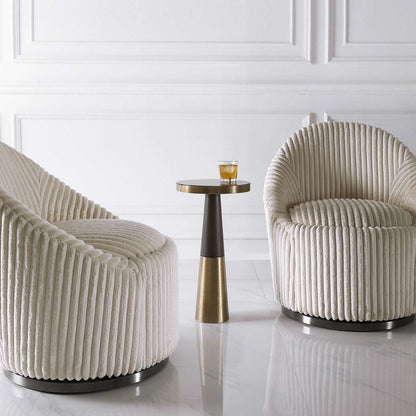 Brass contemporary drink table with cocktail glass and two white decorative chairs in a living room with marble floors.