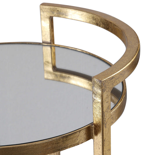 Gold leaf frame on surface of table around mirrored surface.