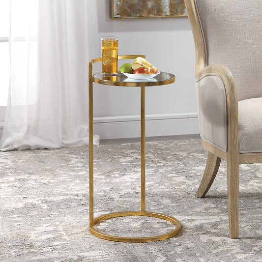 Gold leaf end table with a mirrored surface with a cup of iced tea and plate of fruit.