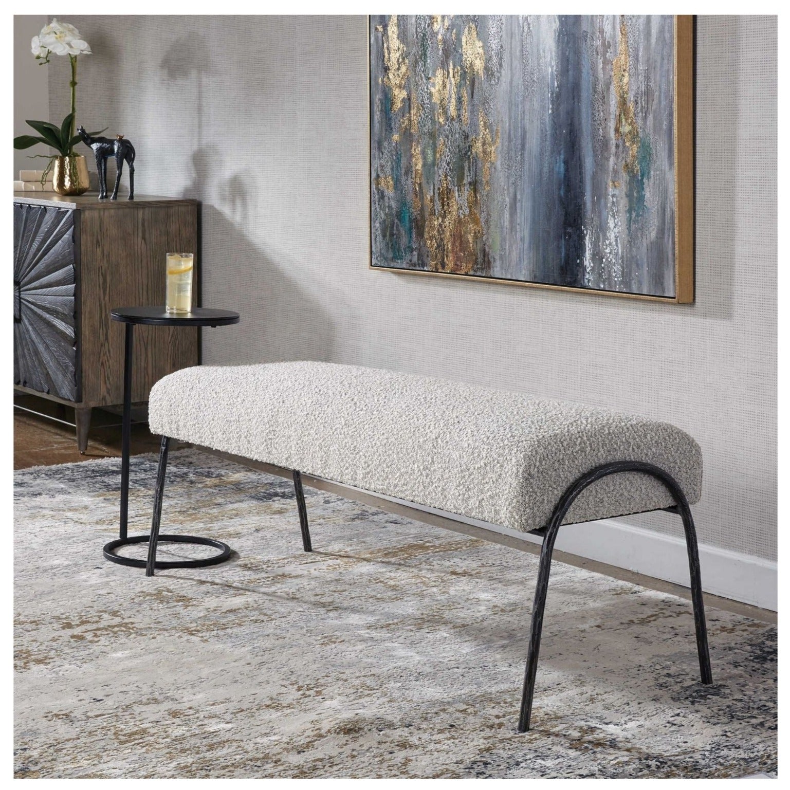 Gray boucle living room bench with neutral rug and abstract art in a chic living room.