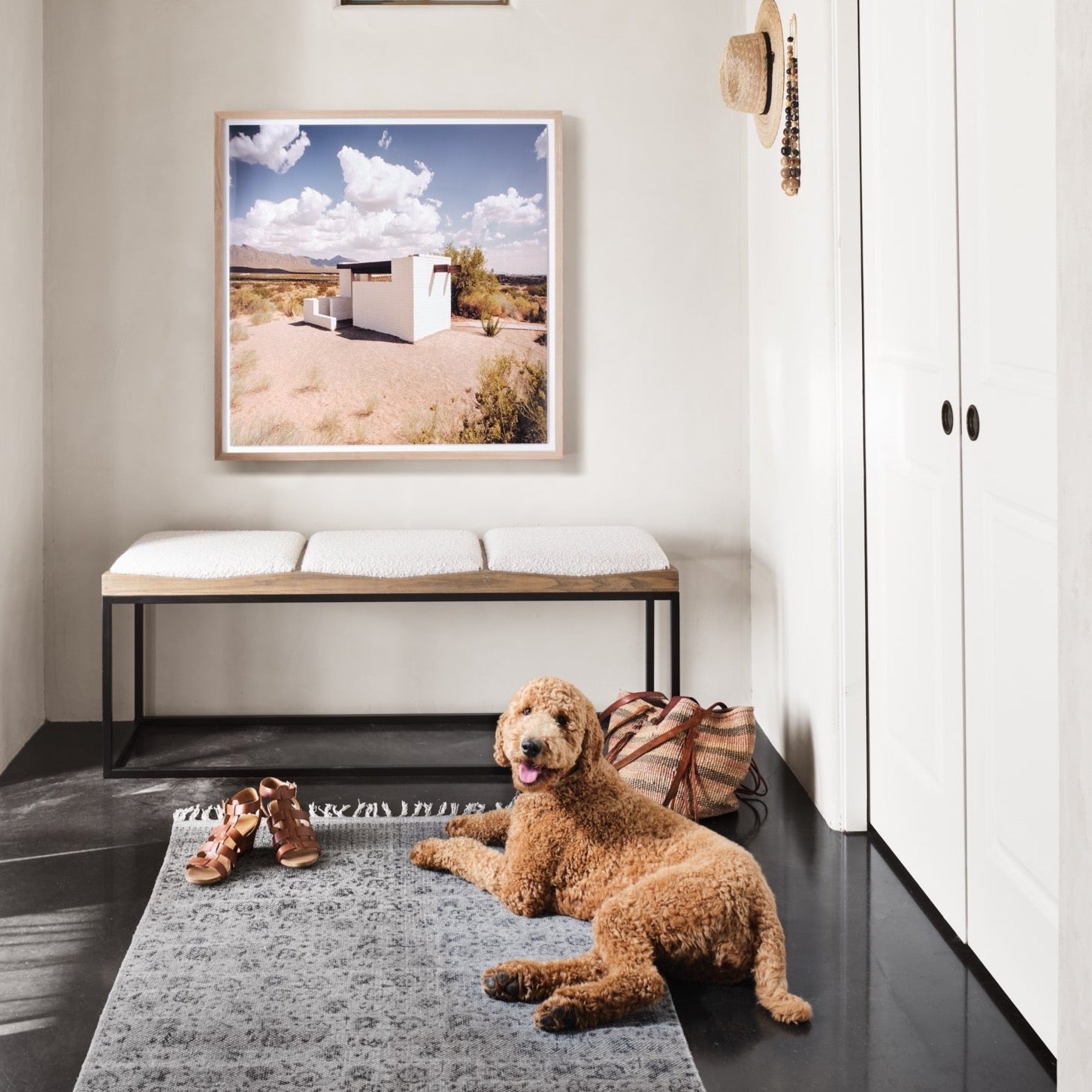 Tri-seat boucle entryway bench with rug and dog in the entryway of a home with a photo of marfa.