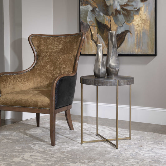 White rug, tan chair, a round dark woo side table with brass accents.